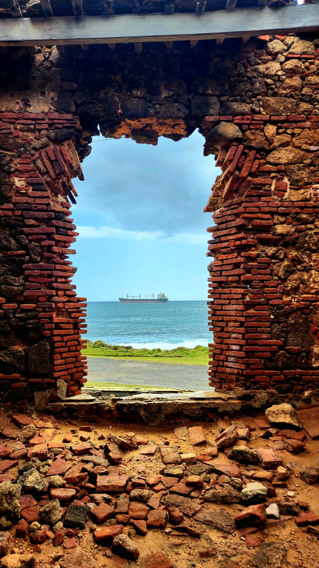 Brick archway framing a cruise ship docked in San Juan bay